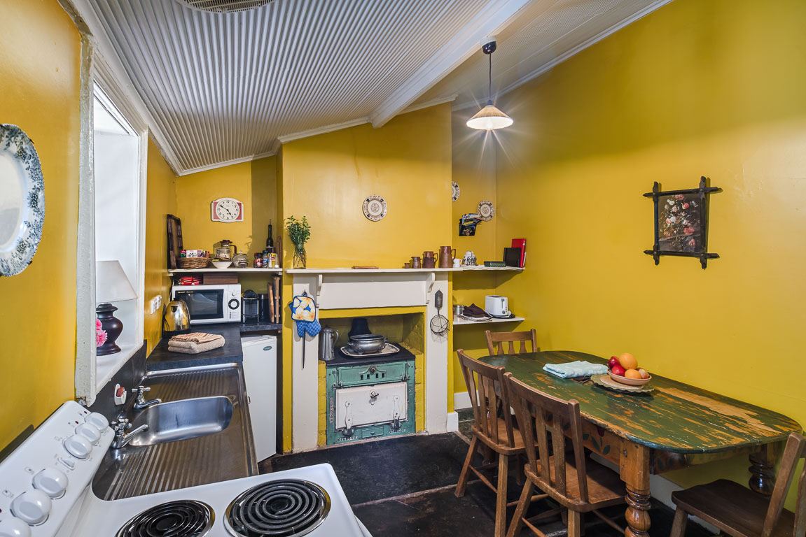 Cottage 8's kitchen with mustard walls, oven, kettle and a dining table set for four
