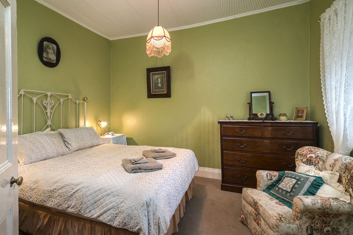 The queen bedroom with a made bed, folded towels and a lamp on the bedside table