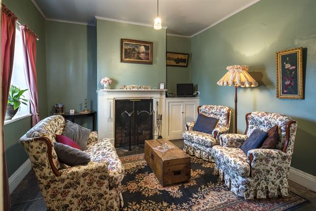 Cottage 10 — the cottage parlour with its open fireplace and armchairs